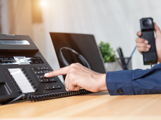 Person wählt Nummer am Telefon Person hält Telefon und wählt Nummer